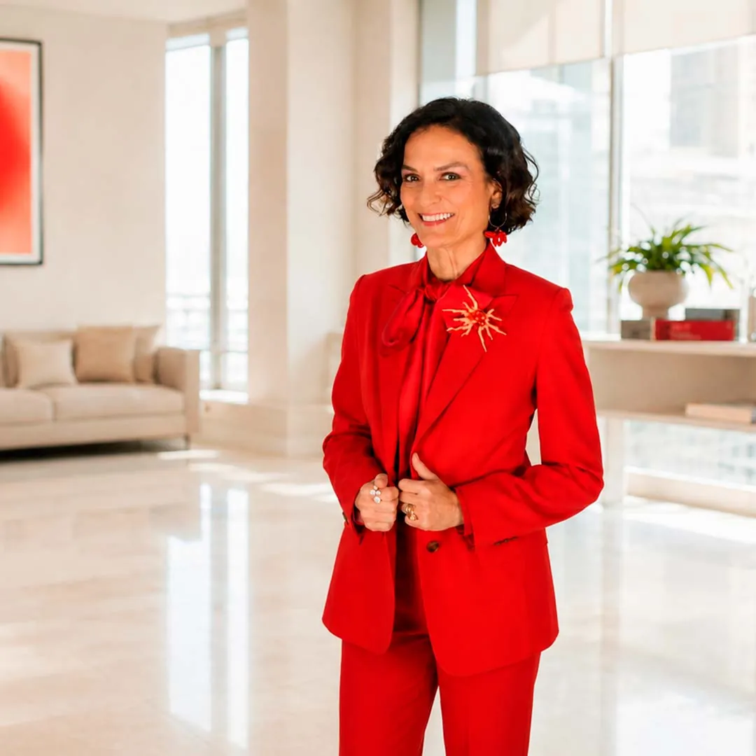 Asun Arias, con traje rojo, en un salón luminoso